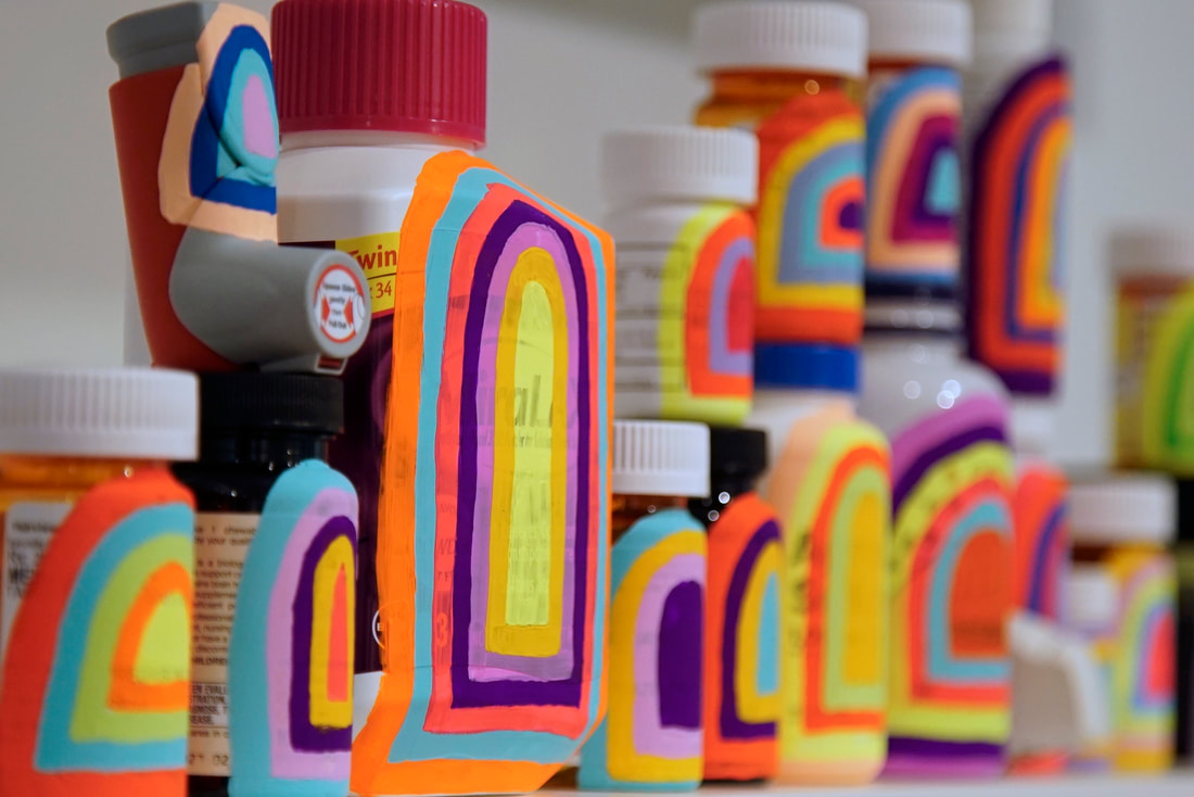 Line of Kelley's portals, used prescription and supplement bottles (and inhalers) painted in bright, neon concentric archway or portal shapes.